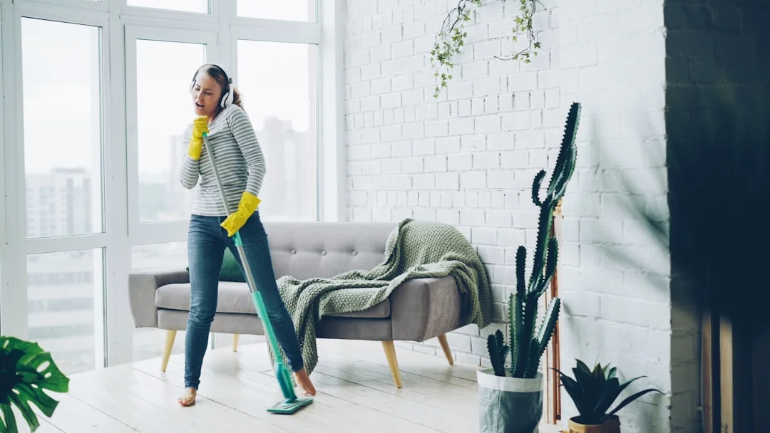 A trained cleaner wearing protective equipment vacuuming the floor in a contemporary living room.